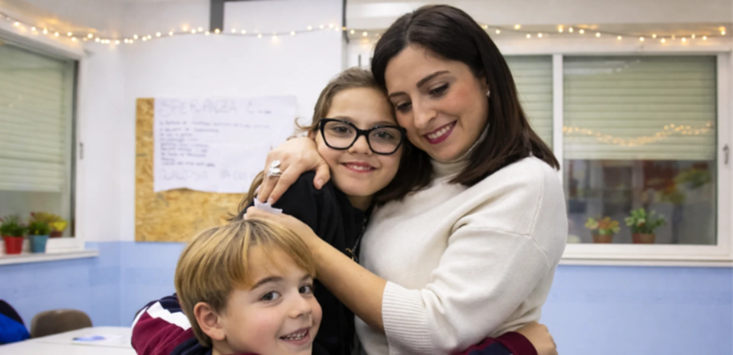 operatrice sociale che abbraccia due bambini