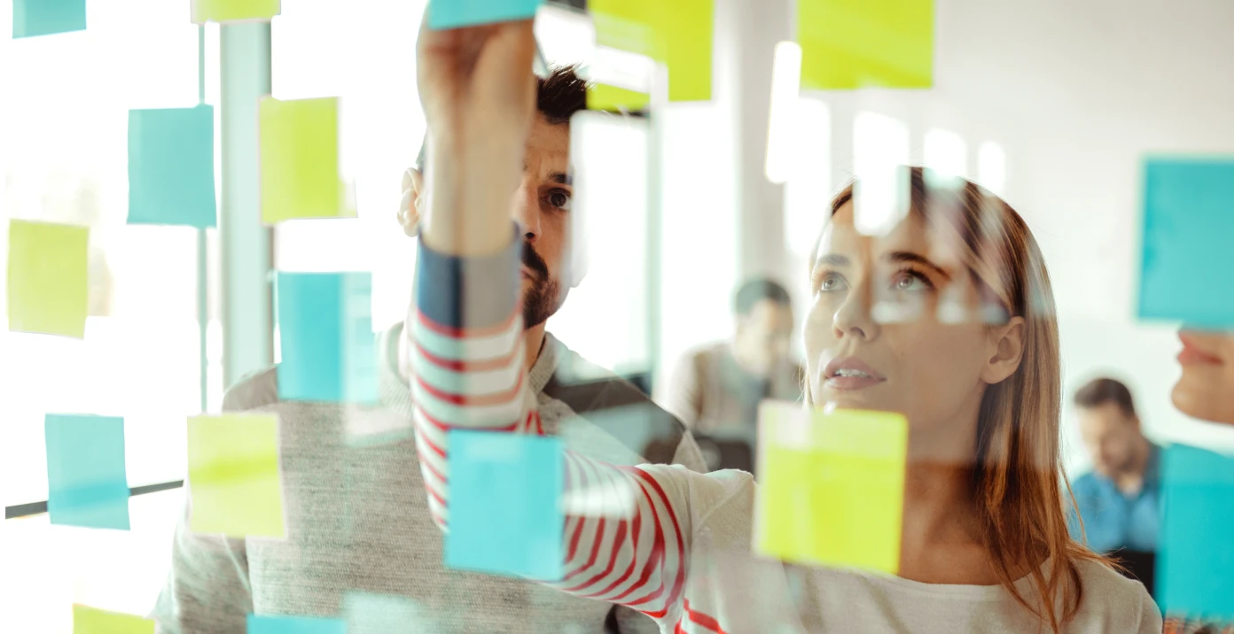 due colleghi di lavoro che sistemano dei post it su un muro