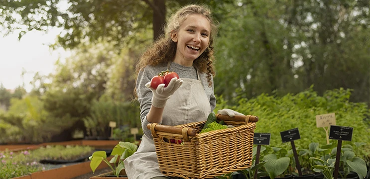 Immagine giovane donna in un orto che raccoglie pomodori