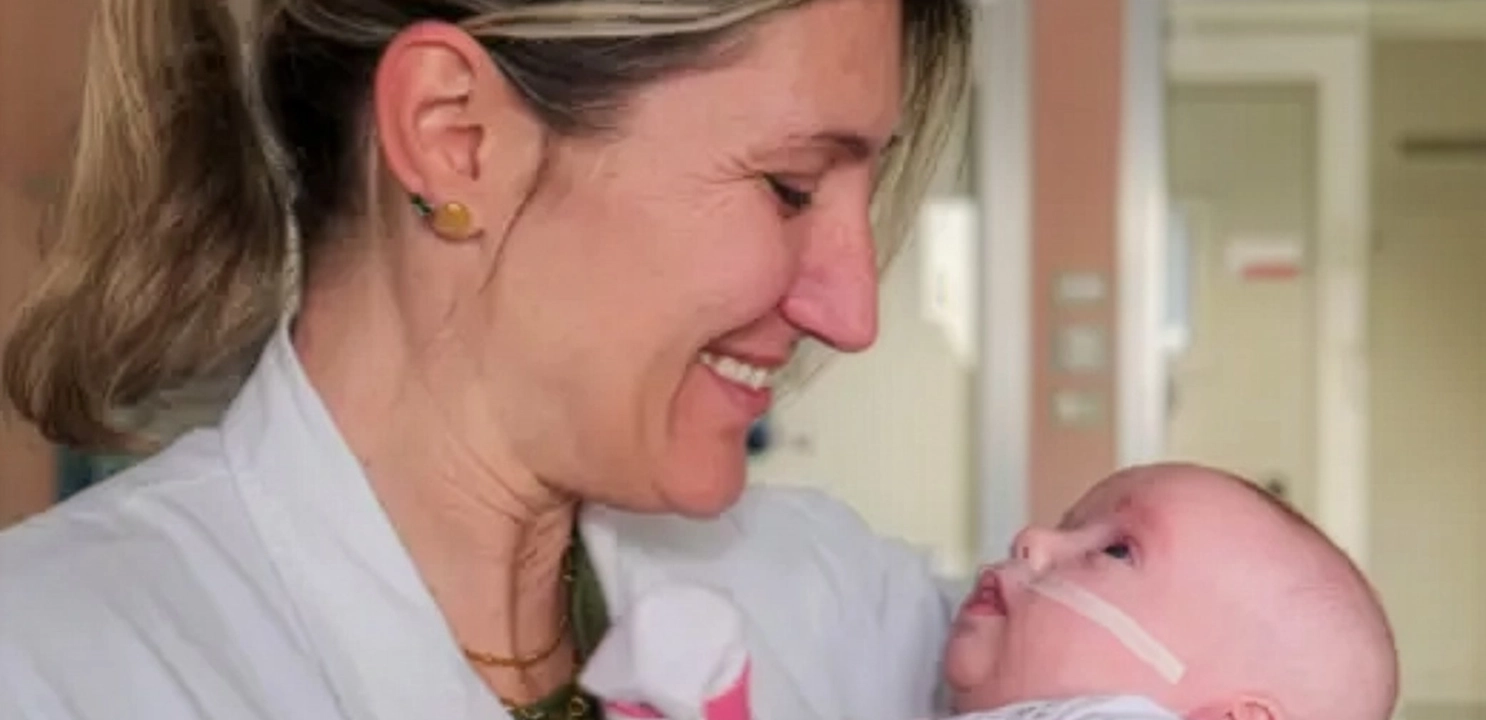 dottoressa che sorride a un neonato che ha in braccio