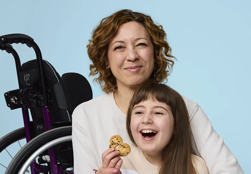 donna con bambina e sedia a rotelle sullo sfondo