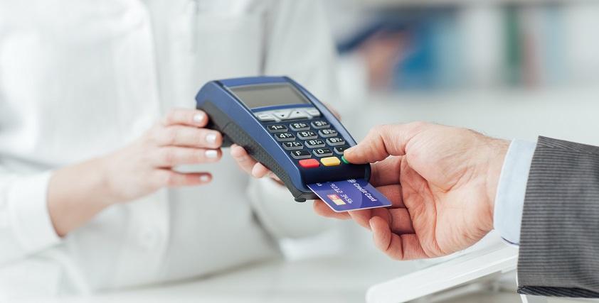 Man making purchases at the drugstore, he is paying with a credit card and using a terminal