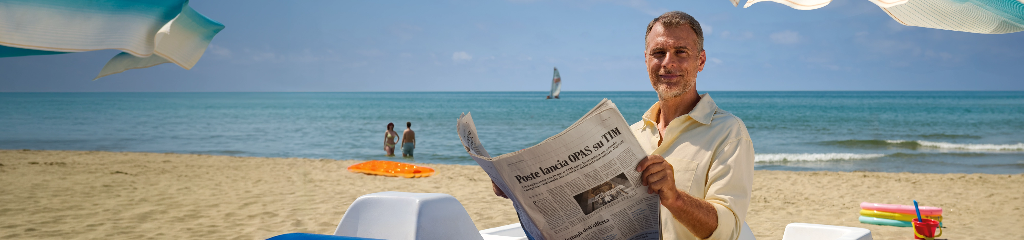 Uomo in spiaggia che legge il giornale