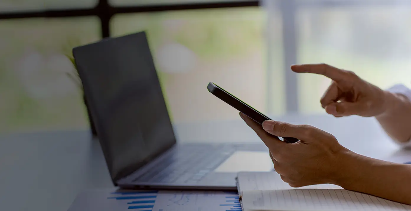 Mani con smartphone e laptop